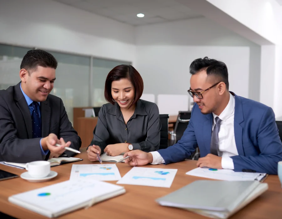 multiethnic-male-female-colleagues-sitting-office-discussing-charts-meeting